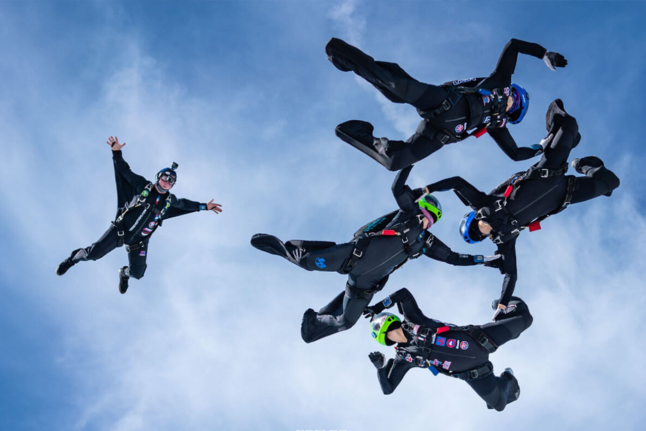 Outside view of a videographer capturing a competitive skydiving team in formation during freefall