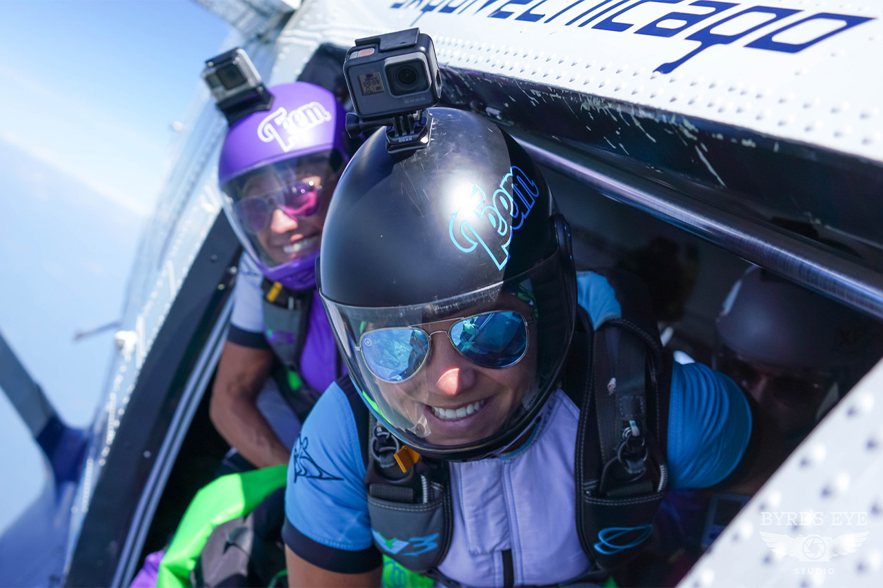 Two licensed skydivers in the door of an airplane preparing to exit