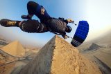 Skydiver with black and blue canopy flying around the Egyptian pyramids