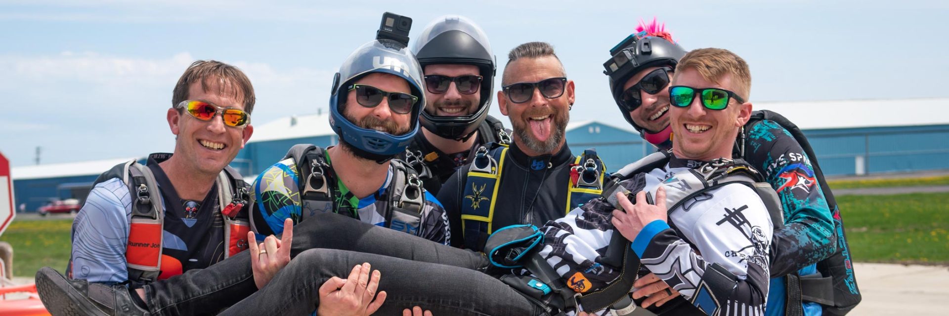 Group of experienced male skydivers posing for a photo on the runway