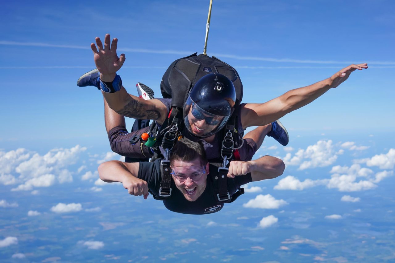 Tandem skydiving student and instructor in freefall with blue sky background