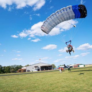 Tandem skydiving student and instructor coming in for landing in a grassy field