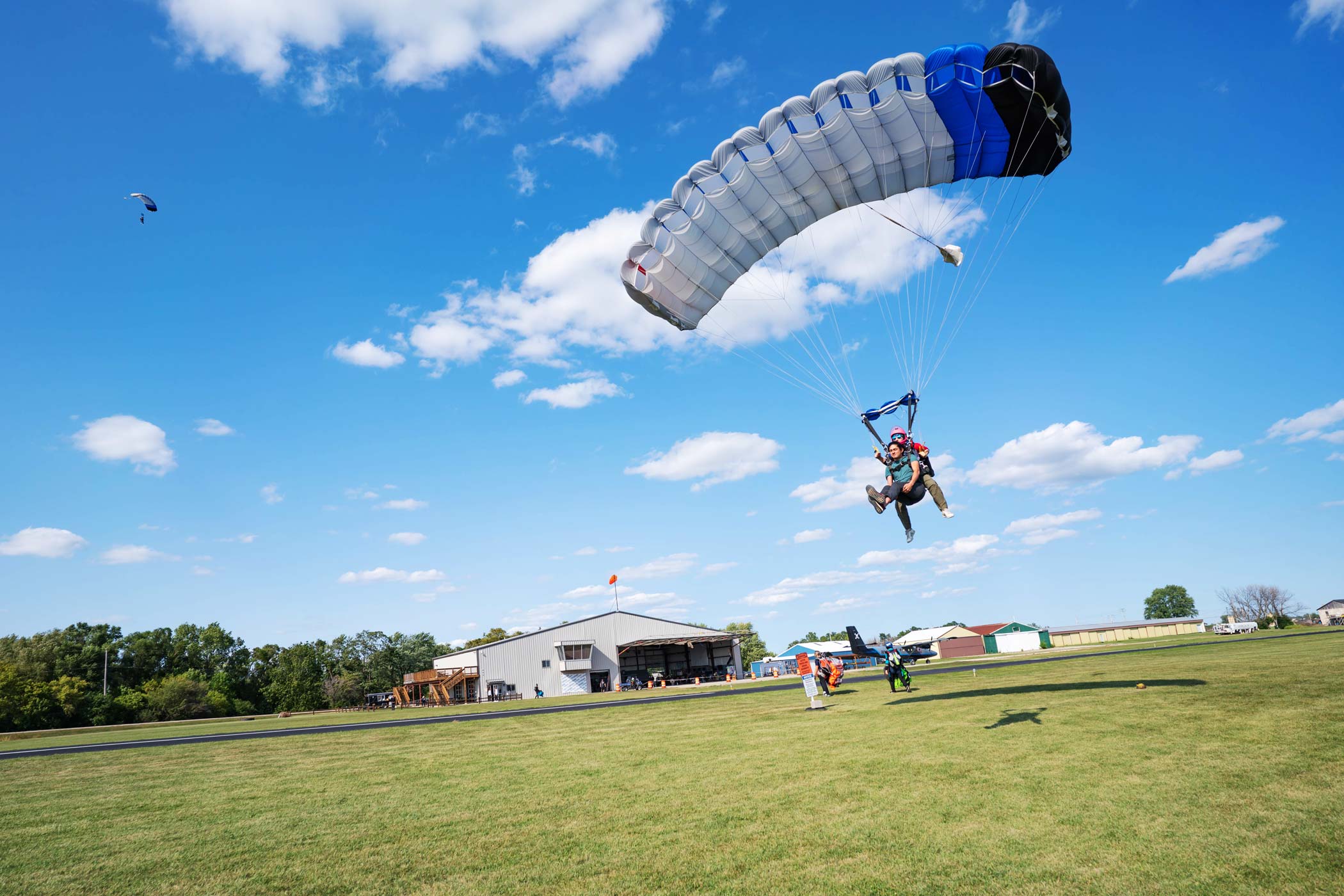 Tandem skydiving student and instructor coming in for landing in a grassy field