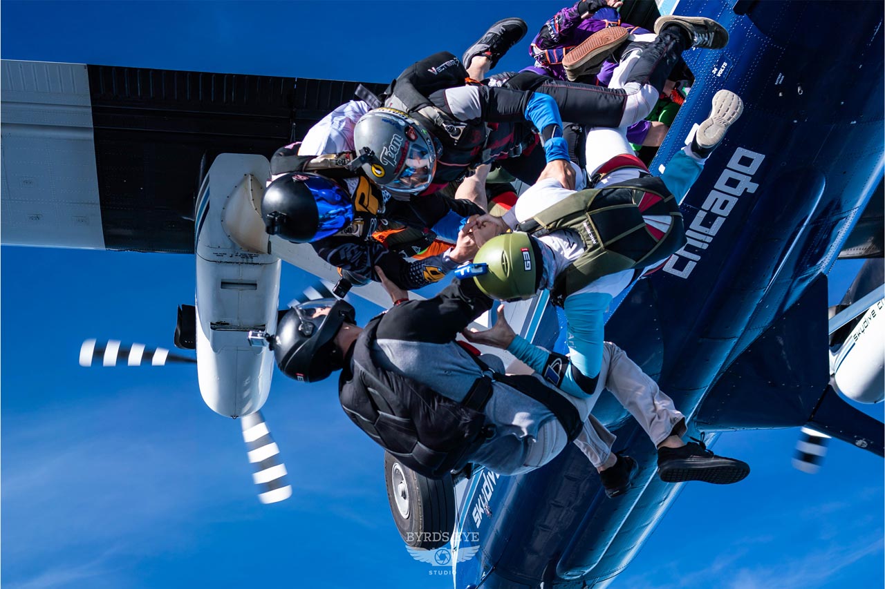 A group of licensed skydivers exiting an airplane in formation