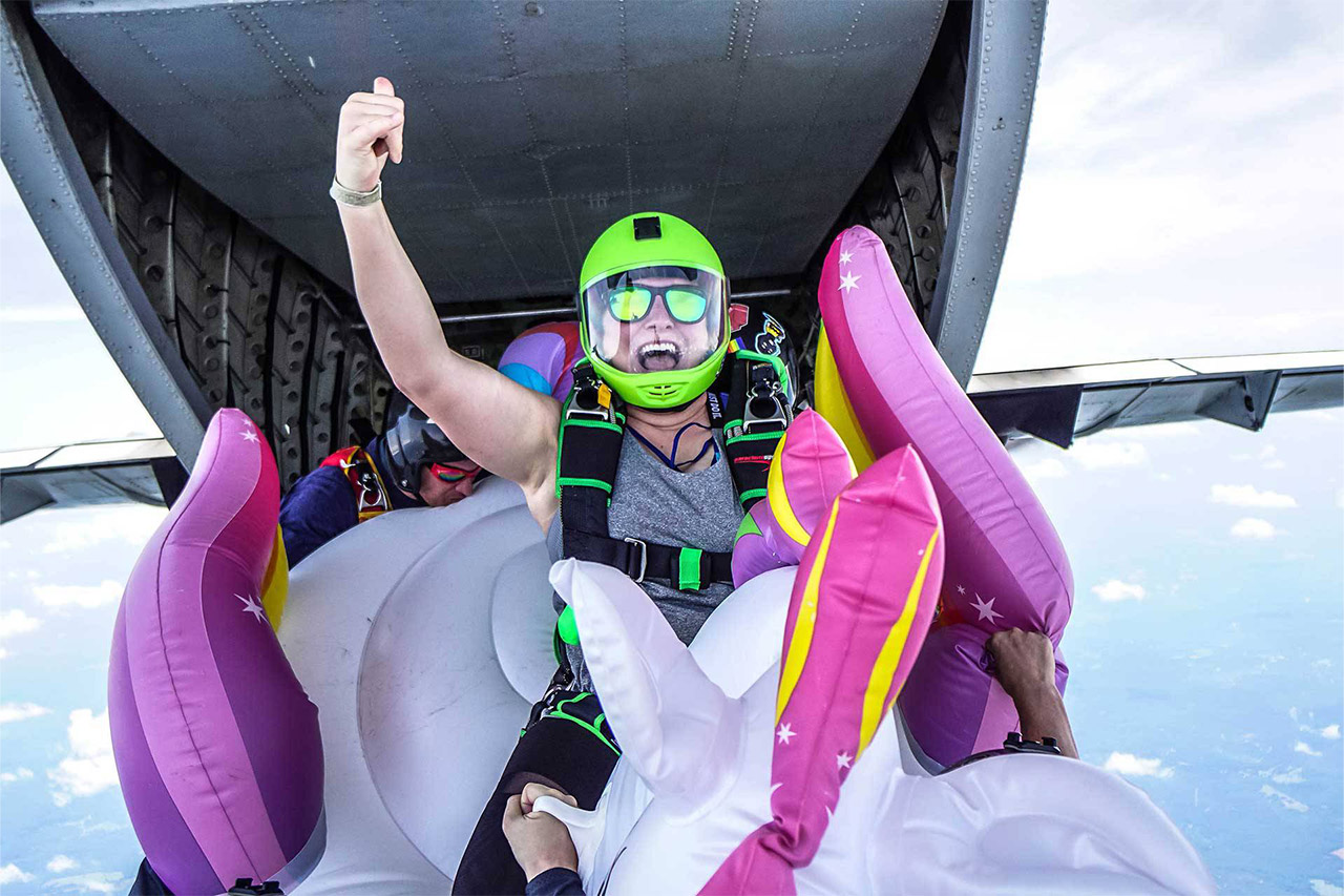 Licensed skydiver exiting an airplane while riding an inflatable unicorn