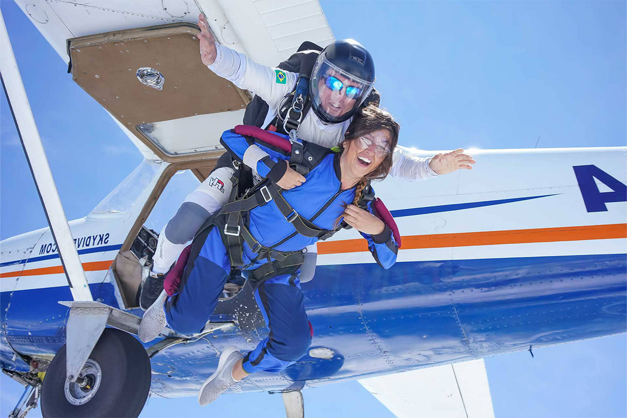 Tandem skydiving student and instructor exiting an airplane